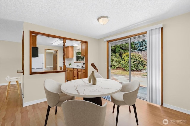 20608 1st Ave S, Des Moines, WA 98198 - dining room with light wood finished floors, a textured ceiling, and baseboards
