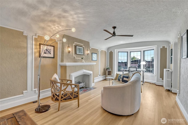 1101 17th Ave Unit 403, Seattle, WA 98122 - living room featuring light wood-type flooring, a large fireplace, a ceiling fan, vaulted ceiling, and a textured ceiling