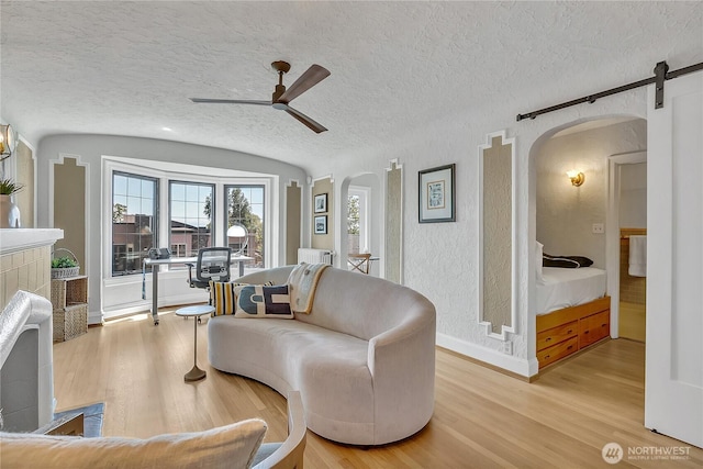 1101 17th Ave Unit 403, Seattle, WA 98122 - living area with arched walkways, ceiling fan, light wood-style flooring, baseboards, and a textured ceiling