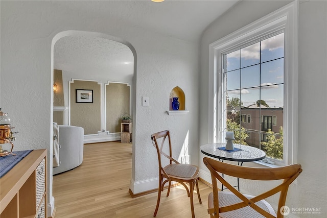 1101 17th Ave Unit 403, Seattle, WA 98122 - dining space with a textured wall, arched walkways, light wood-style flooring, and baseboards