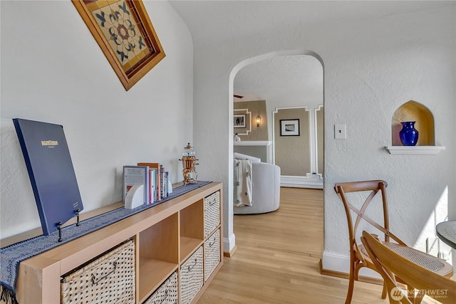 1101 17th Ave Unit 403, Seattle, WA 98122 - hallway with arched walkways, a textured wall, baseboards, and wood finished floors