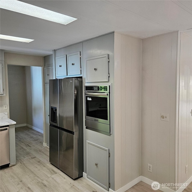 7031 NE 175th St Unit 20, Kenmore, WA 98028 - kitchen featuring stainless steel appliances, light wood finished floors, light stone counters, and baseboards