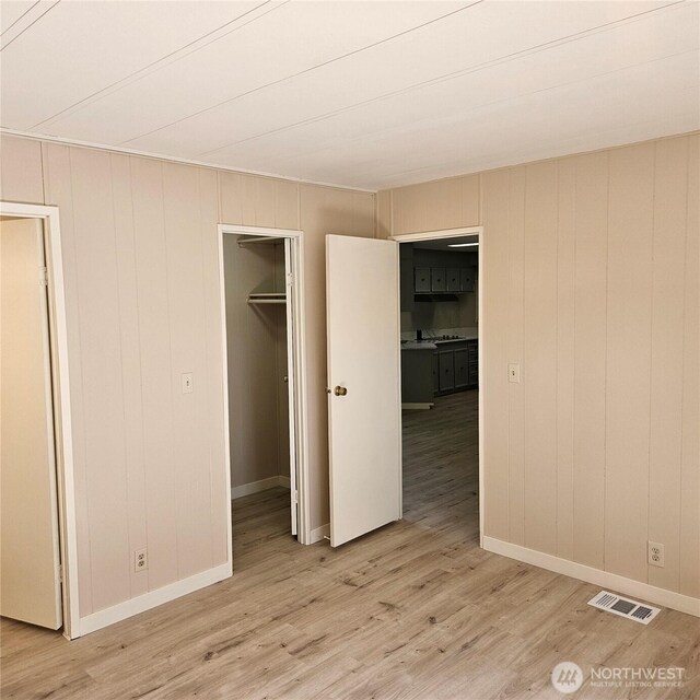7031 NE 175th St Unit 20, Kenmore, WA 98028 - unfurnished bedroom with light wood-style flooring, a walk in closet, baseboards, and a closet