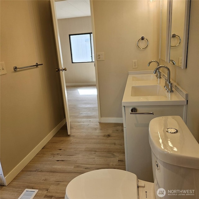 7031 NE 175th St Unit 20, Kenmore, WA 98028 - bathroom featuring wood finished floors, baseboards, double vanity, and toilet