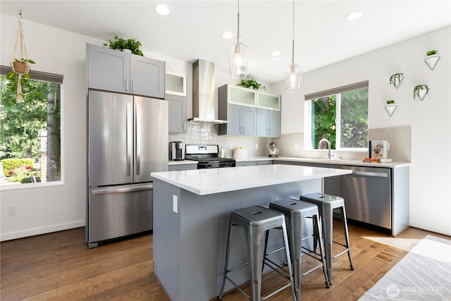 2736 SW Holden St, Seattle, WA 98126 - kitchen with appliances with stainless steel finishes, wall chimney range hood, decorative backsplash, a kitchen breakfast bar, and recessed lighting