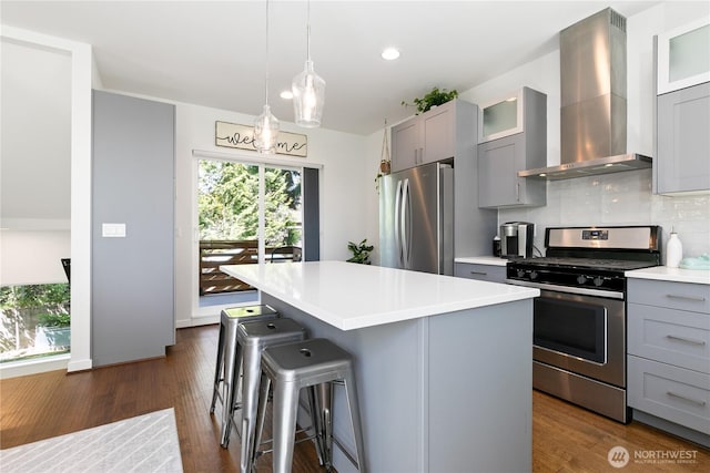 2736 SW Holden St, Seattle, WA 98126 - kitchen featuring appliances with stainless steel finishes, wall chimney range hood, gray cabinets, a center island, and a breakfast bar