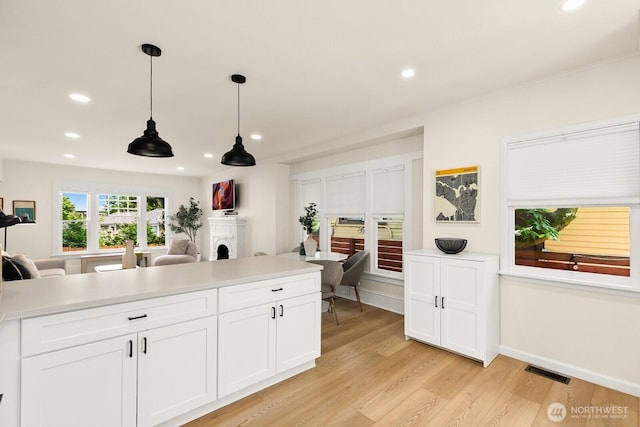 4607 1st Ave NE, Seattle, WA 98105 - kitchen with light wood-style flooring, a fireplace, recessed lighting, decorative light fixtures, and light countertops