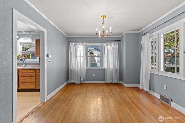 912 Highland Dr, Wenatchee, WA 98801 - unfurnished dining area featuring light wood-style floors, a chandelier, crown molding, baseboards, and a sink