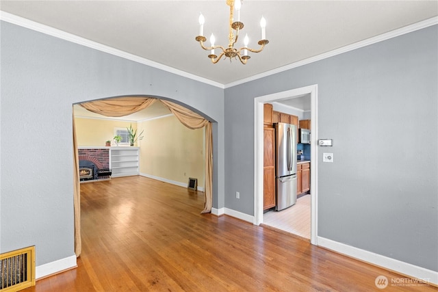 912 Highland Dr, Wenatchee, WA 98801 - unfurnished room with arched walkways, a chandelier, light wood-style flooring, ornamental molding, and baseboards