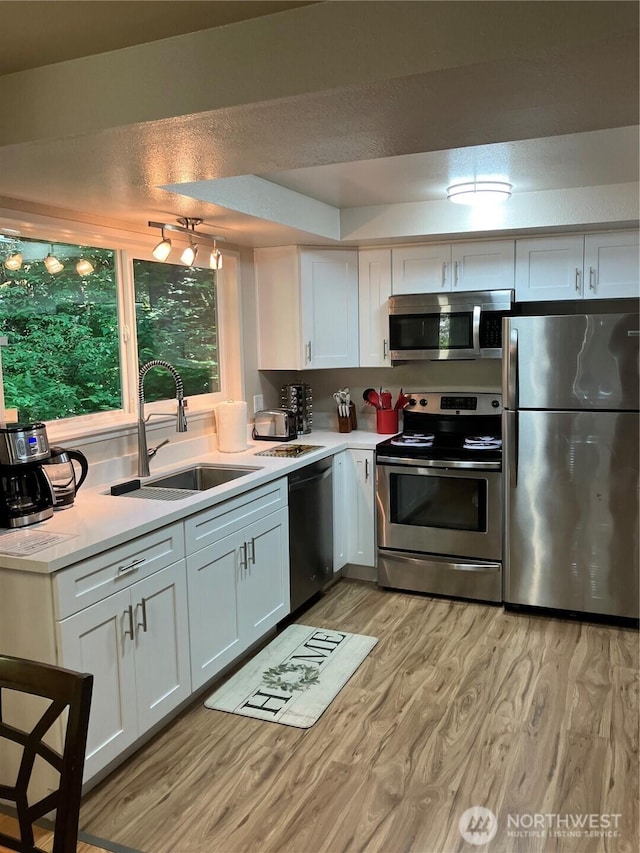64455 NE 180th St, Baring, WA 98224 - kitchen featuring appliances with stainless steel finishes, a sink, light countertops, light wood-style flooring, and white cabinetry