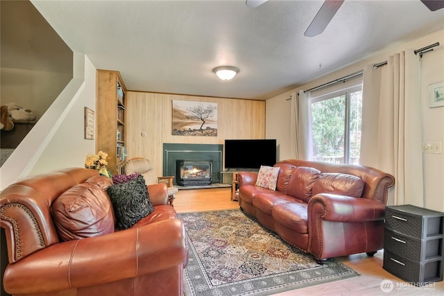 64455 NE 180th St, Baring, WA 98224 - living room featuring wood finished floors, a ceiling fan, wooden walls, and a glass covered fireplace