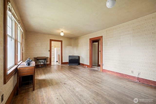 208 Carolina St, Bellingham, WA 98225 - living room with wood finished floors, healthy amount of natural light, a wood stove, wallpapered walls, and baseboards