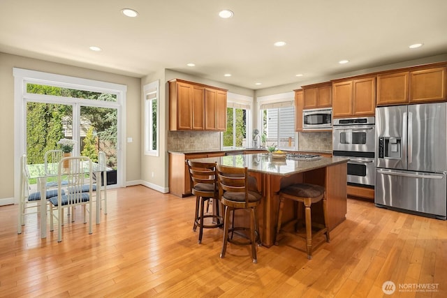 27528 SE 28th Ct, Sammamish, WA 98075 - kitchen with appliances with stainless steel finishes, brown cabinetry, a center island, decorative backsplash, and recessed lighting