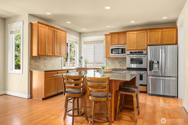 27528 SE 28th Ct, Sammamish, WA 98075 - kitchen with stainless steel appliances, light wood-style flooring, decorative backsplash, dark stone counters, and recessed lighting