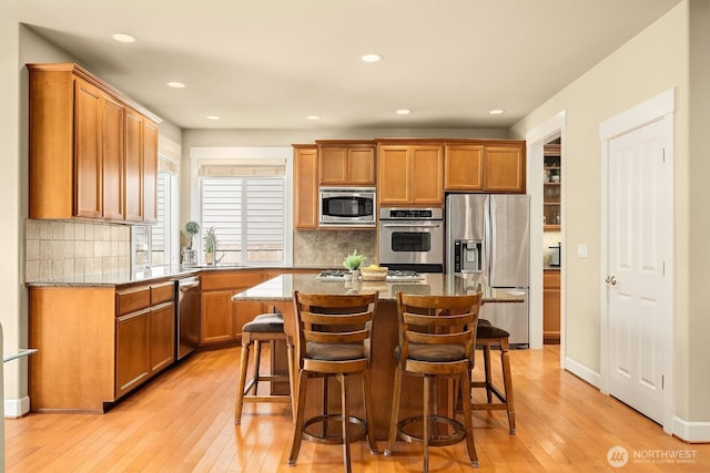 27528 SE 28th Ct, Sammamish, WA 98075 - kitchen featuring stainless steel appliances, light wood-style flooring, a sink, stone countertops, and a breakfast bar