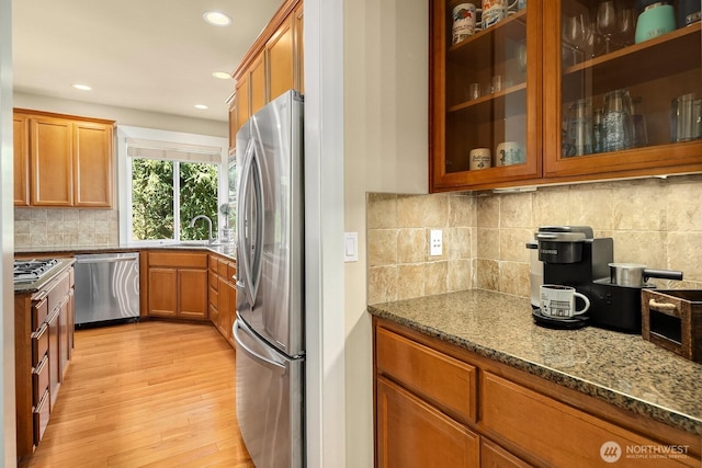 27528 SE 28th Ct, Sammamish, WA 98075 - kitchen featuring appliances with stainless steel finishes, a sink, dark stone counters, light wood finished floors, and brown cabinets