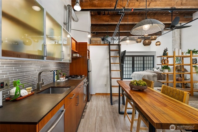 1505 11th Ave Unit 310, Seattle, WA 98122 - kitchen with dark countertops, a sink, light wood-style floors, tasteful backsplash, and beamed ceiling