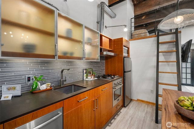 1505 11th Ave Unit 310, Seattle, WA 98122 - kitchen featuring stainless steel appliances, a sink, light wood finished floors, dark countertops, and backsplash