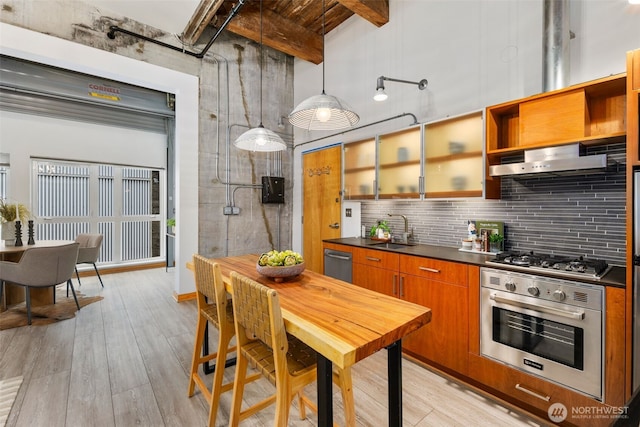 1505 11th Ave Unit 310, Seattle, WA 98122 - kitchen featuring stainless steel appliances, a sink, a towering ceiling, dark countertops, and range hood