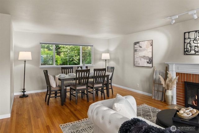 15406 NE 3rd Pl, Bellevue, WA 98007 - dining area with a fireplace, wood finished floors, track lighting, and baseboards