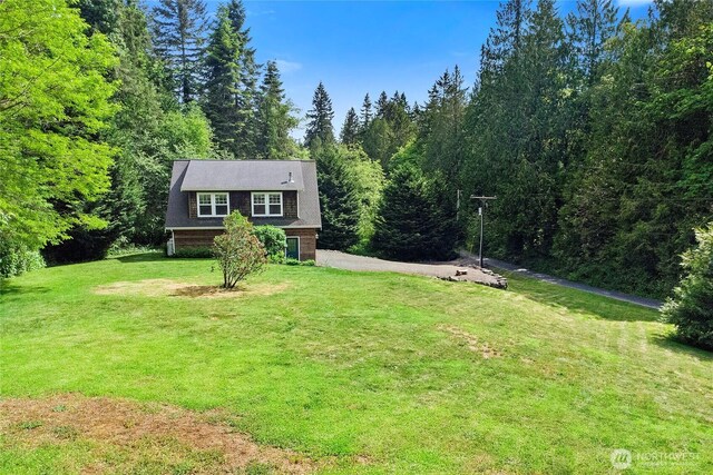 8000 NE W Port Madison Rd, Bainbridge Island, WA 98110 - view of front of property with asphalt driveway, a front lawn, and a wooded view