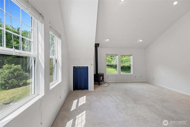 8000 NE W Port Madison Rd, Bainbridge Island, WA 98110 - unfurnished living room featuring a wood stove, light carpet, lofted ceiling, and recessed lighting