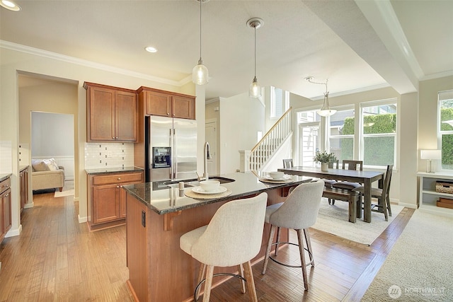 24817 SE 13th Pl, Sammamish, WA 98075 - kitchen with stainless steel refrigerator with ice dispenser, a sink, ornamental molding, brown cabinetry, and a kitchen bar