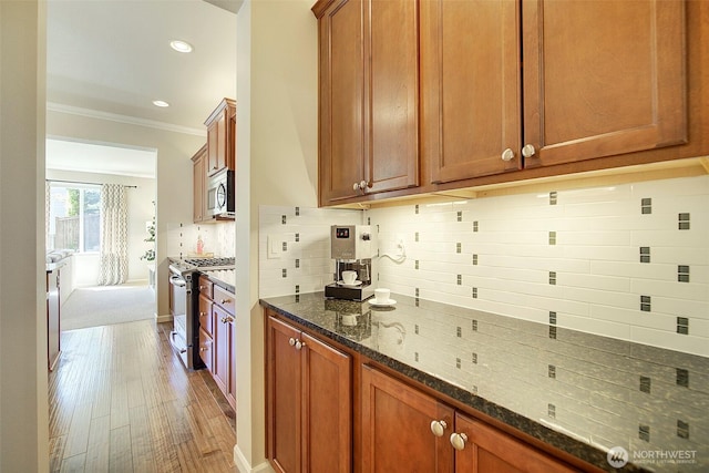 24817 SE 13th Pl, Sammamish, WA 98075 - kitchen featuring appliances with stainless steel finishes, ornamental molding, dark stone countertops, light wood finished floors, and tasteful backsplash
