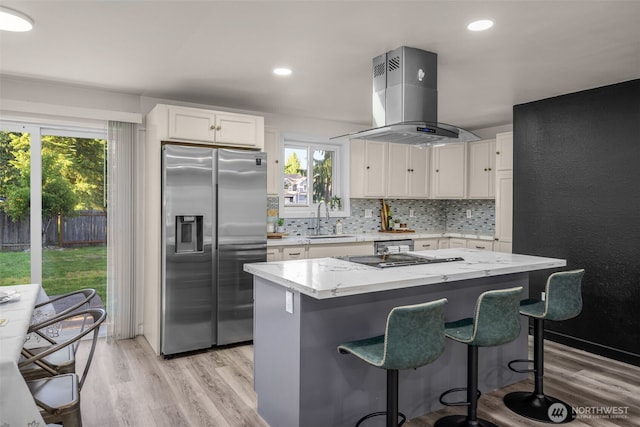 8517 188th Ct E, Puyallup, WA 98375 - kitchen with stainless steel fridge, island exhaust hood, a sink, light wood-style flooring, and white cabinets