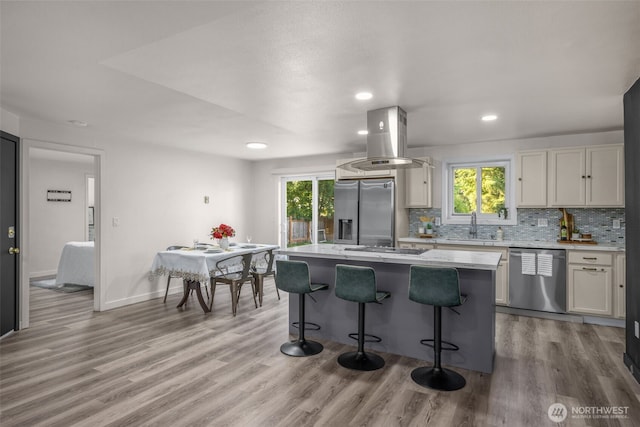 8517 188th Ct E, Puyallup, WA 98375 - kitchen with stainless steel appliances, island range hood, a center island, a kitchen breakfast bar, and decorative backsplash