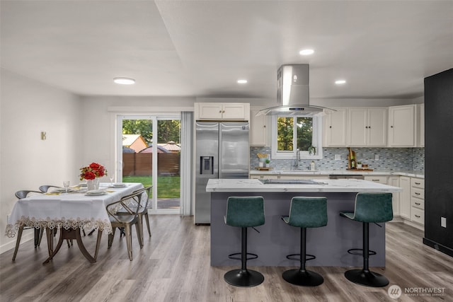 8517 188th Ct E, Puyallup, WA 98375 - kitchen with island exhaust hood, stainless steel fridge with ice dispenser, a kitchen island, white cabinetry, and a kitchen breakfast bar