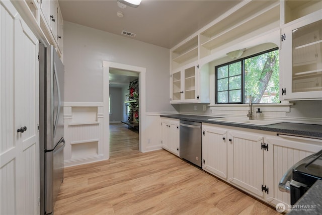 18005 Burn Rd, Arlington, WA 98223 - kitchen with appliances with stainless steel finishes, dark countertops, light wood-style flooring, wainscoting, and white cabinetry