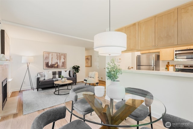 9805 Avondale Rd NE Unit M139, Redmond, WA 98052 - dining room featuring light wood-style floors, a fireplace with raised hearth, and baseboards