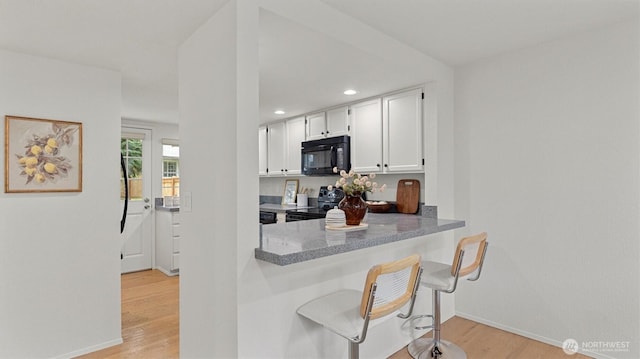 11405 SE 65th St, Bellevue, WA 98006 - kitchen featuring black appliances, white cabinetry, light wood finished floors, recessed lighting, and baseboards