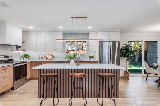 30156 2nd Pl SW, Federal Way, WA 98023 - kitchen featuring appliances with stainless steel finishes, a breakfast bar area, light wood finished floors, light countertops, and decorative backsplash