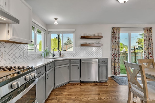 404 Jewell St, Enumclaw, WA 98022 - kitchen with appliances with stainless steel finishes, wall chimney range hood, a sink, gray cabinets, and dark wood-type flooring
