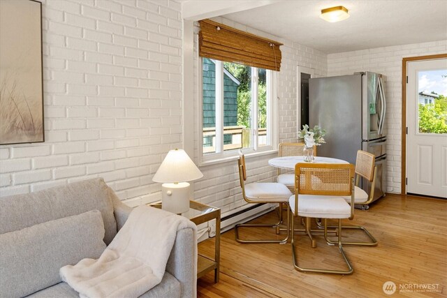 9010 13th Ave SW, Seattle, WA 98106 - dining space with a baseboard radiator, wood finished floors, and brick wall