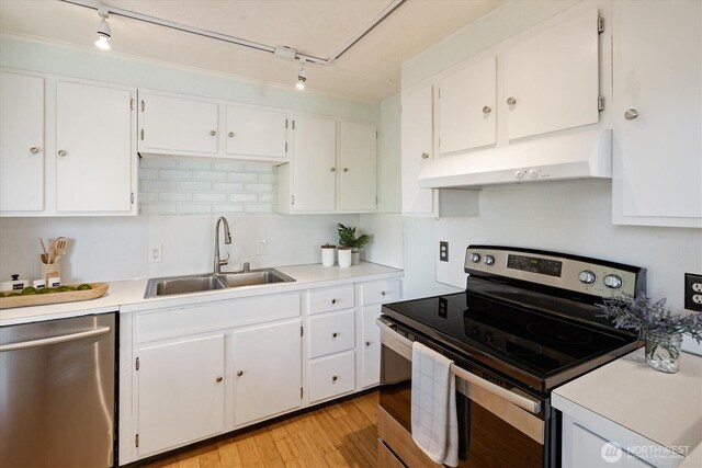 9010 13th Ave SW, Seattle, WA 98106 - kitchen with stainless steel appliances, under cabinet range hood, a sink, track lighting, and white cabinets
