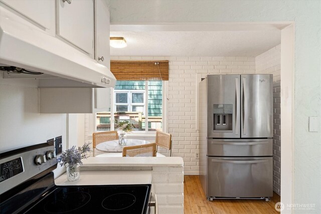 9010 13th Ave SW, Seattle, WA 98106 - kitchen with stainless steel fridge with ice dispenser, electric range, under cabinet range hood, light wood-type flooring, and white cabinets