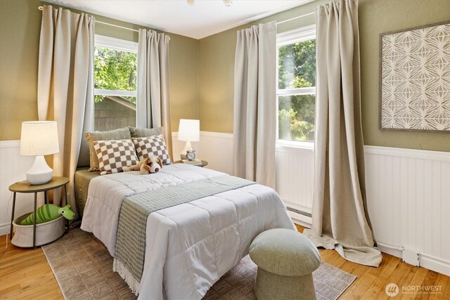 9010 13th Ave SW, Seattle, WA 98106 - bedroom with multiple windows, a wainscoted wall, wood finished floors, and a baseboard radiator