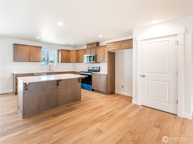 10 Salmon Dr, Wenatchee, WA 98801 - kitchen with appliances with stainless steel finishes, a center island, light wood-style floors, a sink, and light countertops