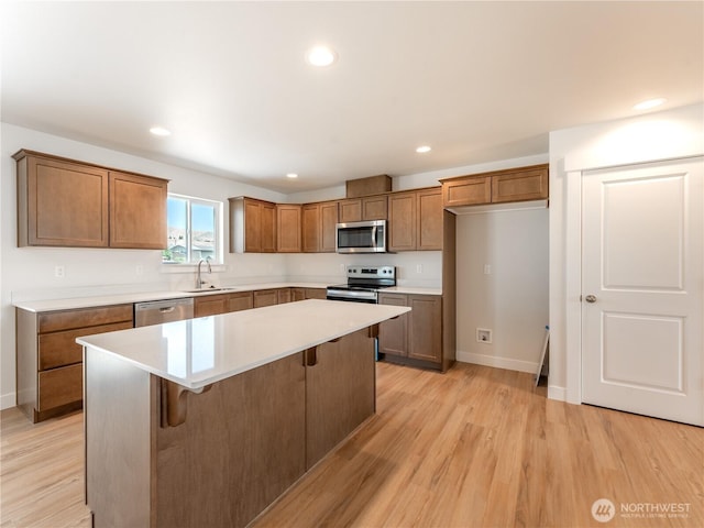 10 Salmon Dr, Wenatchee, WA 98801 - kitchen featuring stainless steel appliances, a sink, brown cabinetry, a kitchen island, and light wood-style floors