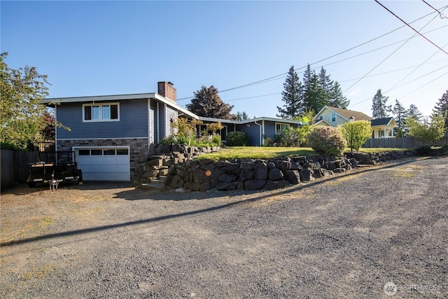 204 76th St SE, Everett, WA 98203 - view of front of house with a chimney, dirt driveway, an attached garage, and stone siding