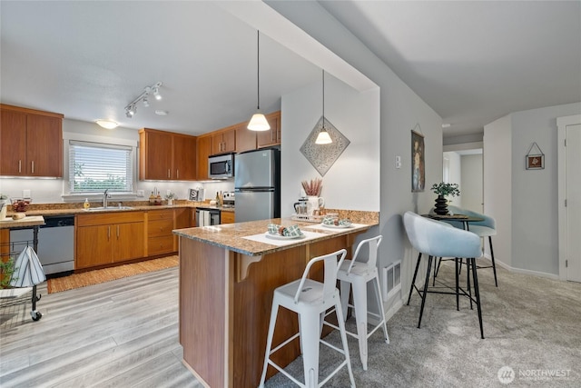 5822 N 35th St Unit C9, Tacoma, WA 98407 - kitchen featuring stainless steel appliances, a sink, a kitchen bar, a peninsula, and brown cabinets