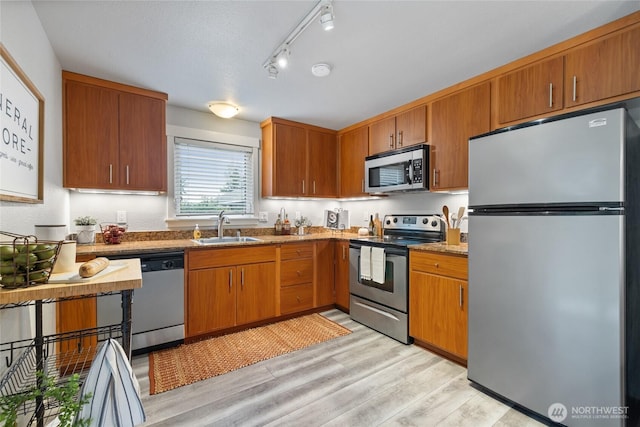 5822 N 35th St Unit C9, Tacoma, WA 98407 - kitchen featuring appliances with stainless steel finishes, a sink, light wood-style flooring, and brown cabinetry