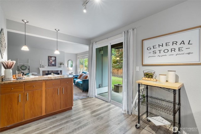 5822 N 35th St Unit C9, Tacoma, WA 98407 - kitchen featuring light wood-style floors, brown cabinets, a fireplace, open floor plan, and decorative light fixtures