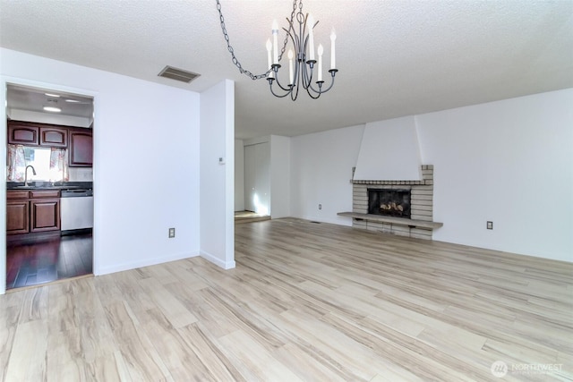 32622 39th Ave SW, Federal Way, WA 98023 - unfurnished living room with a chandelier, wood finished floors, a sink, a textured ceiling, and a large fireplace