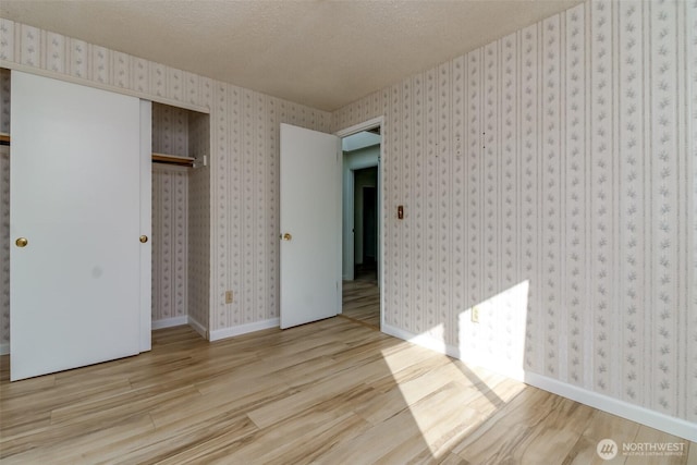 32622 39th Ave SW, Federal Way, WA 98023 - unfurnished bedroom featuring wood finished floors, a closet, a textured ceiling, baseboards, and wallpapered walls