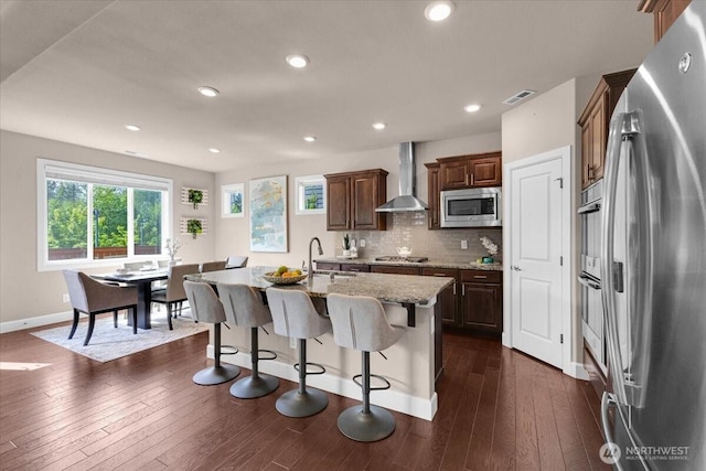 17518 39th Ave SE, Bothell, WA 98012 - kitchen featuring stainless steel appliances, wall chimney exhaust hood, baseboards, light stone countertops, and a breakfast bar area