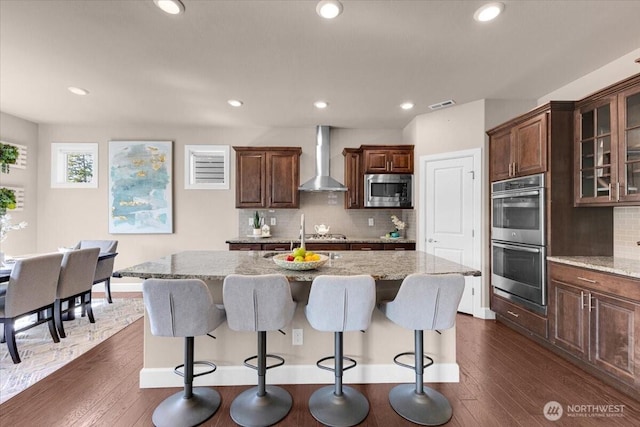 17518 39th Ave SE, Bothell, WA 98012 - kitchen with appliances with stainless steel finishes, wall chimney range hood, a kitchen bar, light stone counters, and recessed lighting